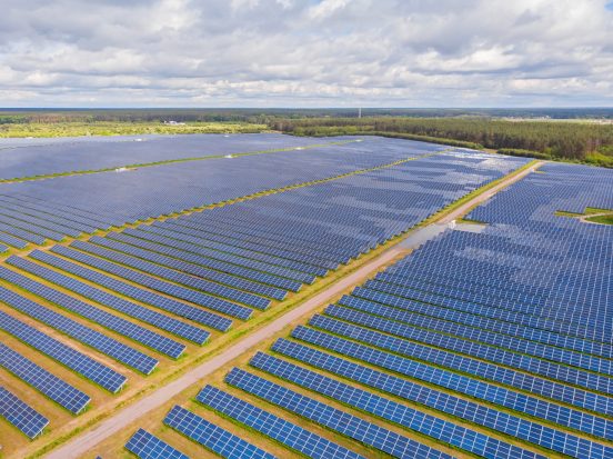 Solar panel produces green, environmentaly friendly energy from the setting sun. Aerial view from drone. Landscape picture of a solar plant that is located inside a valley